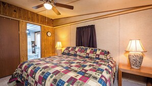A bedroom with a wooden ceiling fan, a quilted bedspread, two bedside lamps, and a wooden nightstand. - Charming Canal Waterfront 3/2 in Salt Springs (Salt Springs)