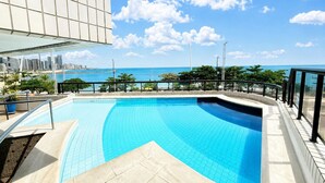 A swimming pool with a view of the ocean and a city skyline.