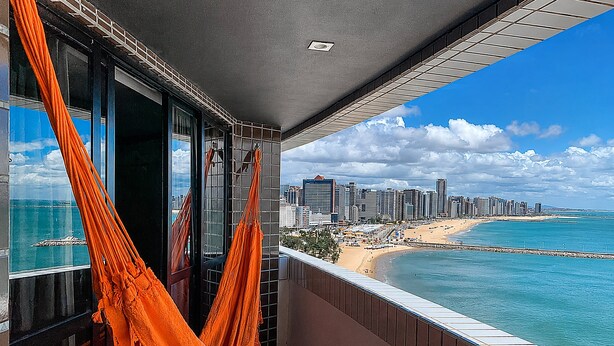 A balcony with a view of a beach and city skyline.