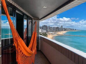 Un balcon avec vue sur une plage et sur les bâtiments de la ville.
