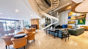 A spacious lobby with a spiral staircase, seating areas, and artwork on the walls.