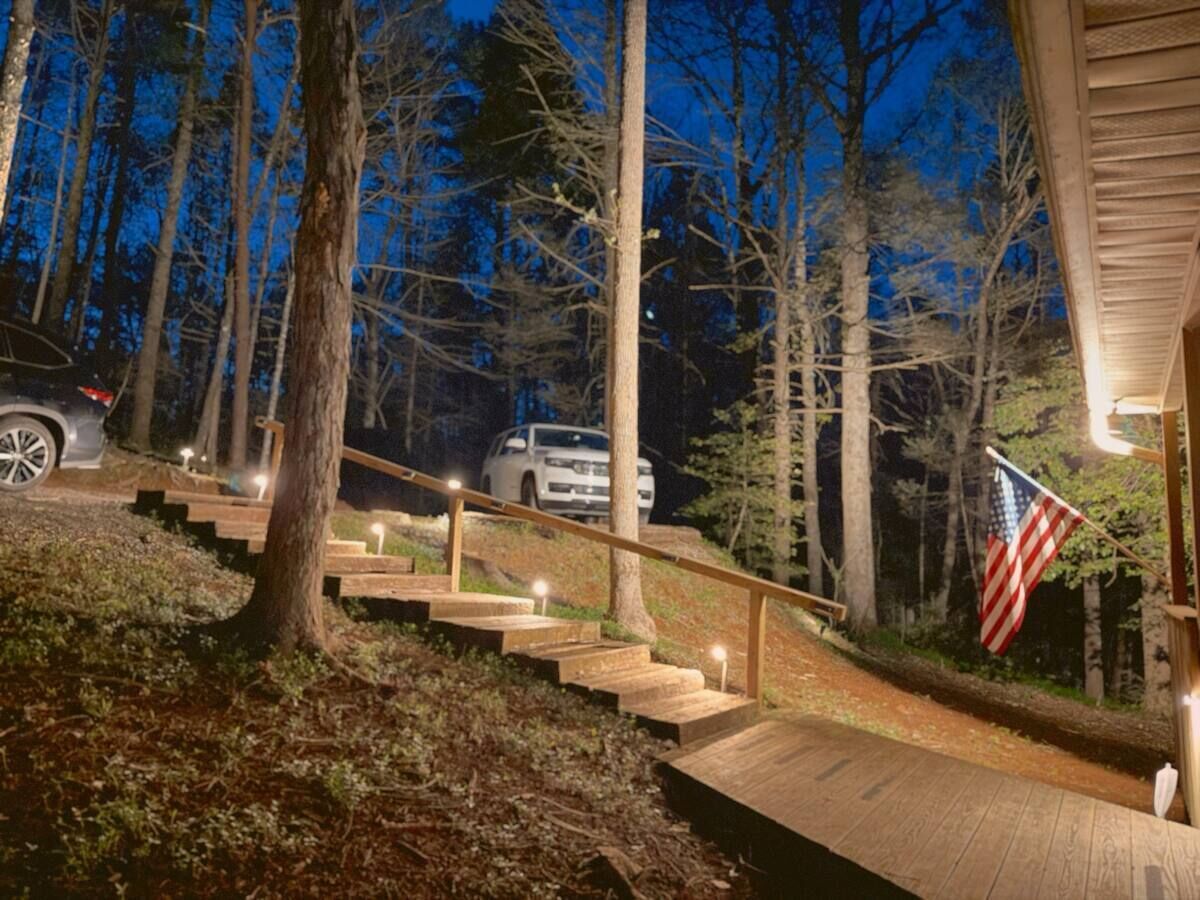 A wooden staircase leading to a house with an American flag, surrounded by trees.