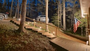 A wooden staircase leading to a house with an American flag, surrounded by trees.