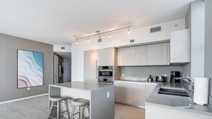 A modern kitchen with a central island, stainless steel appliances, and a minimalist design. - Miami Escape, 16th Floor – Near Hollywood Beach (Hollywood)