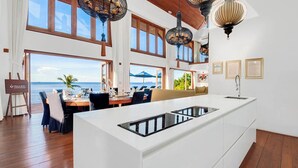 Een moderne keuken met een groot eiland, een eethoek met uitzicht op de oceaan, en een gezellige zithoek met uitzicht op zee.