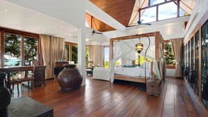 Een ruime slaapkamer met een groot bed, een zithoek met een tafel en stoelen, en uitzicht op de omgeving.