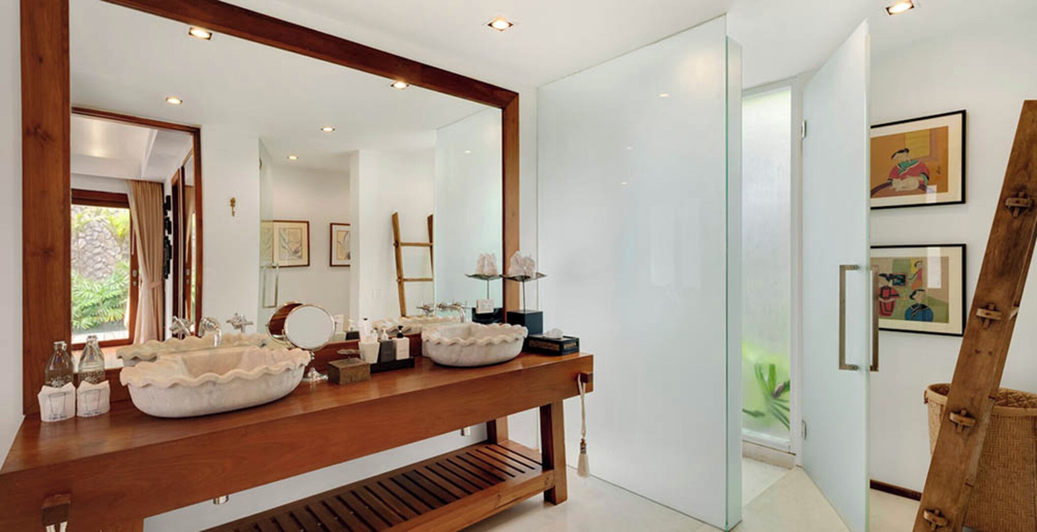 A modern bathroom with two large sinks, a wooden vanity, a large mirror, and a glass shower enclosure.