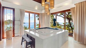 Een moderne badkamer met een groot bad, een bankje en uitzicht op zee.