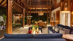 A spacious living area with a blue sofa, wooden beams, a dining table, and a pool in the background. - Beautiful 5 Star Villa in a Prime Location in Seminyak, Bali Villa 2129 (Bali)