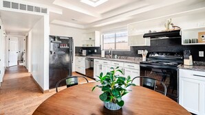 A modern kitchen with white cabinets, a black stove, and a skylight. - Charming 3-bedroom house in Central location / UofA bike path on Mountain (Tucson)