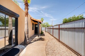 Una casa moderna con patio coperto, una palma e una recinzione in metallo.