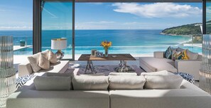 A modern living room with a large window overlooking a beach and ocean. - Your Friends Will Love This Luxury Villa, Fully Staffed and Private Chef, Phuket Villa 1060 (Phuket)