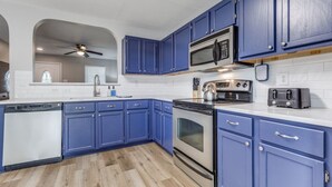 A kitchen with blue cabinets, a microwave, an oven, and a toaster. - Bright, fun, and welcoming home near Lackland and Seaworld (San Antonio)