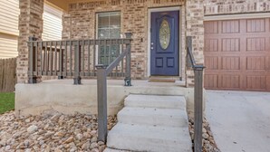 A brick house with a front porch, a dark blue door, and a garage. - Bright, fun, and welcoming home near Lackland and Seaworld (San Antonio)