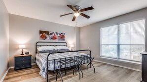 A bedroom with a bed, a nightstand, a ceiling fan, and a window with blinds. - Bright, fun, and welcoming home near Lackland and Seaworld (San Antonio)
