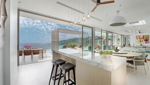 A modern kitchen with a large island, bar stools, and a view of the sea. - Experience the Ultimate Holiday while staying in this Luxury Villa in Phuket, Phuket Villa 1062 (Phuket)