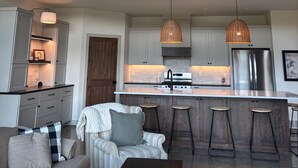 A modern kitchen with a central island, stainless steel appliances, and pendant lighting. - Lake Alexander + Sleeps 4 Families + Lakeside + Fire Pit (Cushing)
