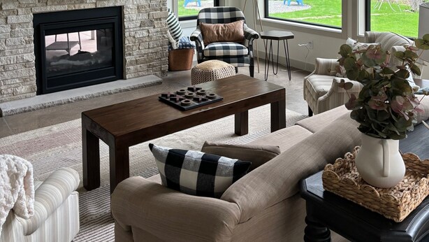 A living room with a stone fireplace, a flat-screen TV, and large windows offering a view of the outdoors. - Lake Alexander + Sleeps 4 Families + Lakeside + Fire Pit (Cushing)