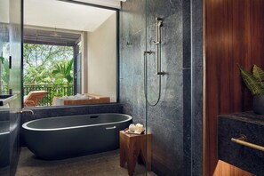 Un baño moderno con una bañera independiente, cabina de ducha con mampara de vidrio y un taburete de madera.