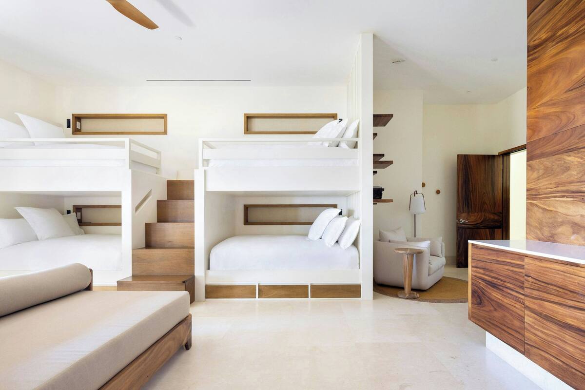 A modern bedroom with bunk beds, a sofa, a small table, and a wooden cabinet.