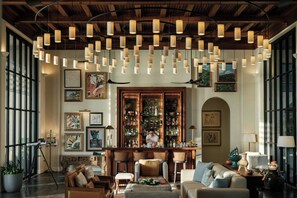 A spacious room with a bar area, large windows, and a high ceiling with exposed beams.
