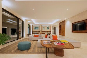 A modern living room with a sofa set, a coffee table, and a TV mounted on the wall.