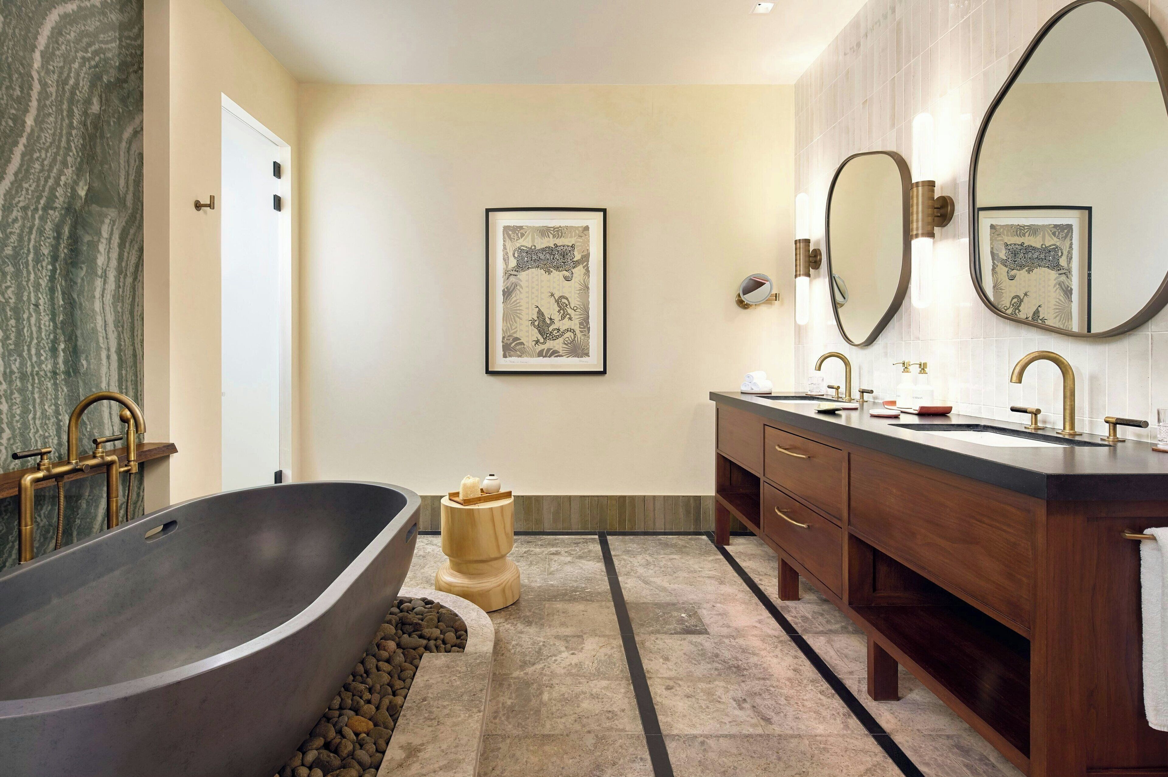 A modern bathroom with a freestanding bathtub, a wooden stool, and a vanity with dual sinks and a large mirror.