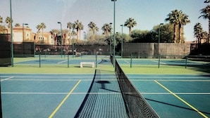 A tennis court with a net, lines, and surrounding greenery. - Coachell - Marriott Shadow Ridge (Palm Desert)