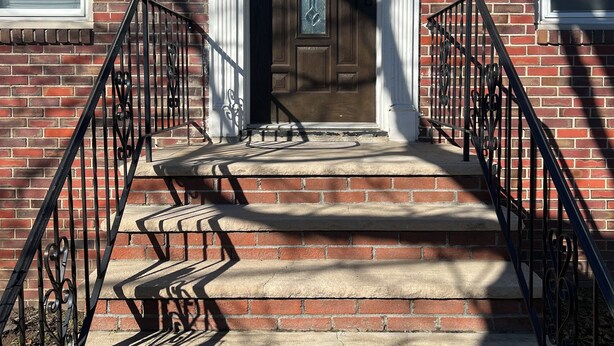 A brick building with a front door, number 51, and a small set of steps leading up to it.