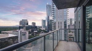 Un immeuble de grande hauteur doté d’une façade en verre et d’un balcon avec une rambarde en métal.