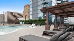 Un espace piscine aménagé sur le toit, avec des chaises longues et une pergola.