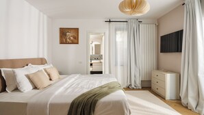 A bedroom with a large bed, a bedside table, a dresser, a mirror, and a ceiling light fixture.