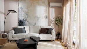 A modern living room with a sofa, a coffee table, a floor lamp, and a large abstract painting on the wall.