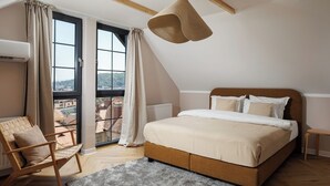 Een slaapkamer met een groot bed, een stoel, een raam met gordijnen en een hanglamp.