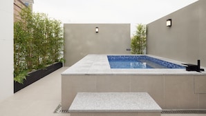 An outdoor swimming pool with a tiled edge, surrounded by low walls and potted plants. - Anook Hotel Suwon Station (Suwon)