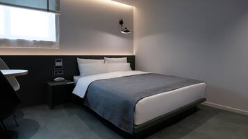 Quarto de hotel moderno com cama bem arrumada, mesa de cabeceira, abajur e janela com persianas.