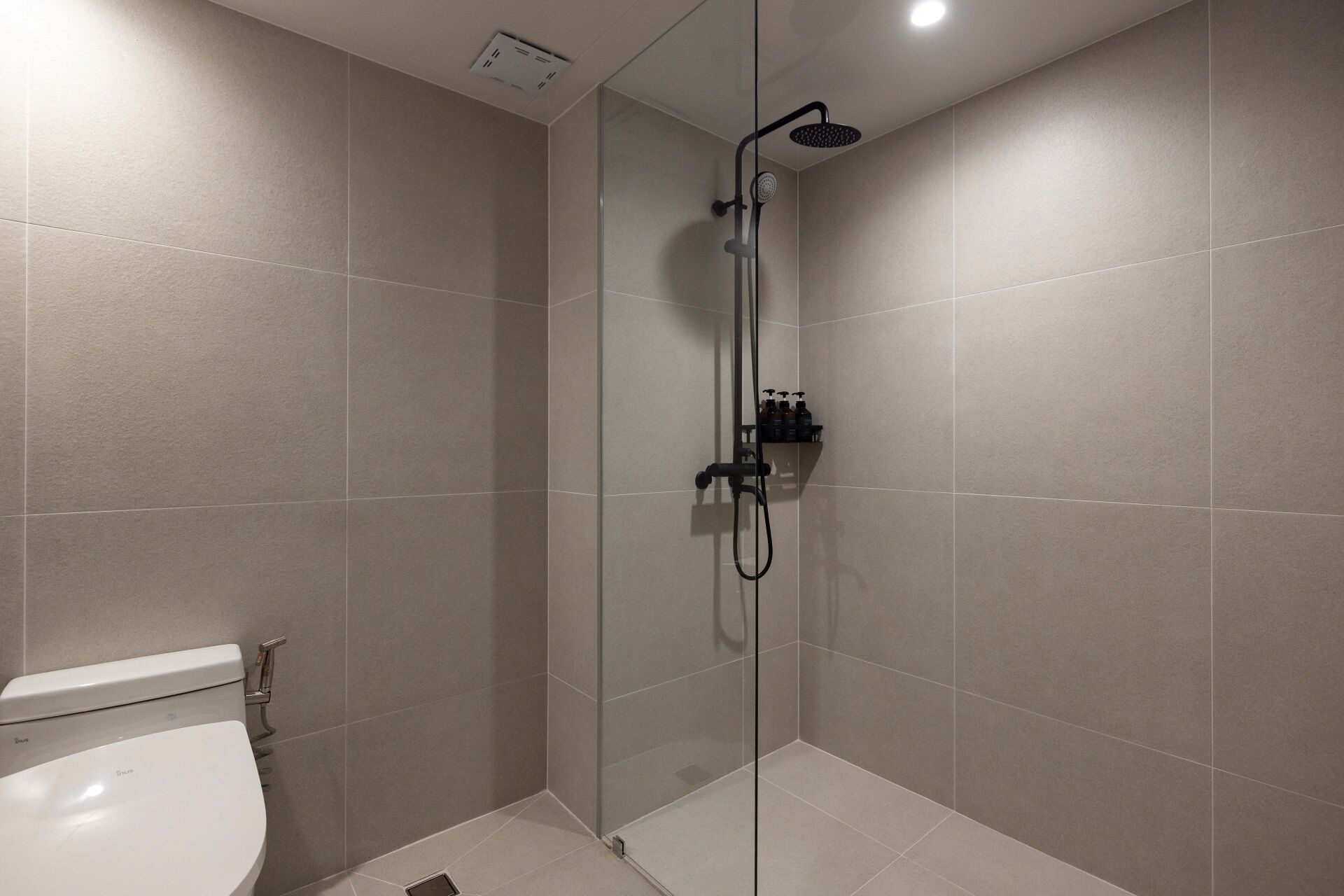 Ein modernes Badezimmer mit einer Duschkabine, einer Toilette und einem Ablagefach für Pflegeartikel.