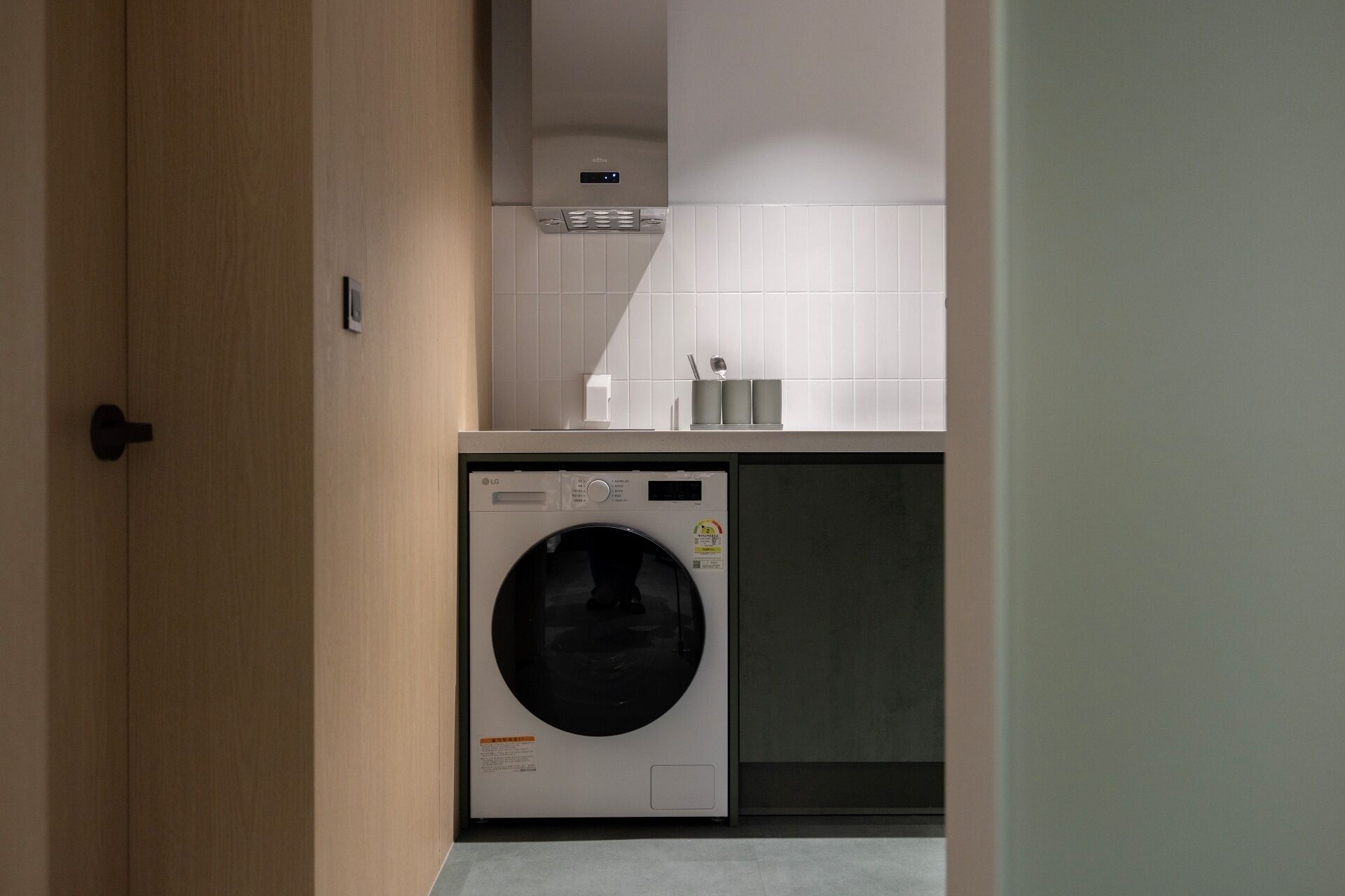 A compact kitchen with a built-in washer and dryer, a small countertop, and a tiled backsplash.