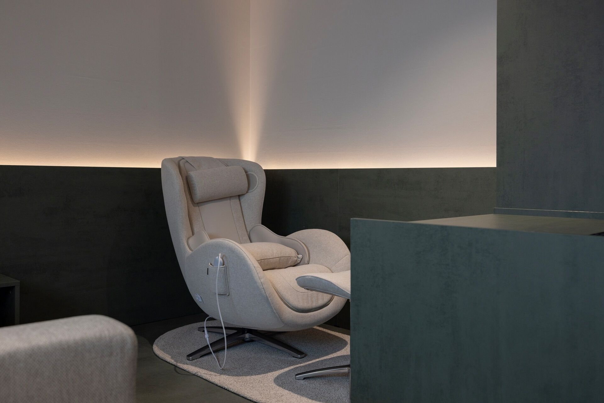 A modern chair with a high backrest and armrests, positioned on a textured rug.