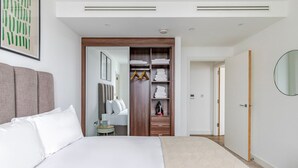 A modern hotel room with a large bed, a walk-in closet, and a mirror.