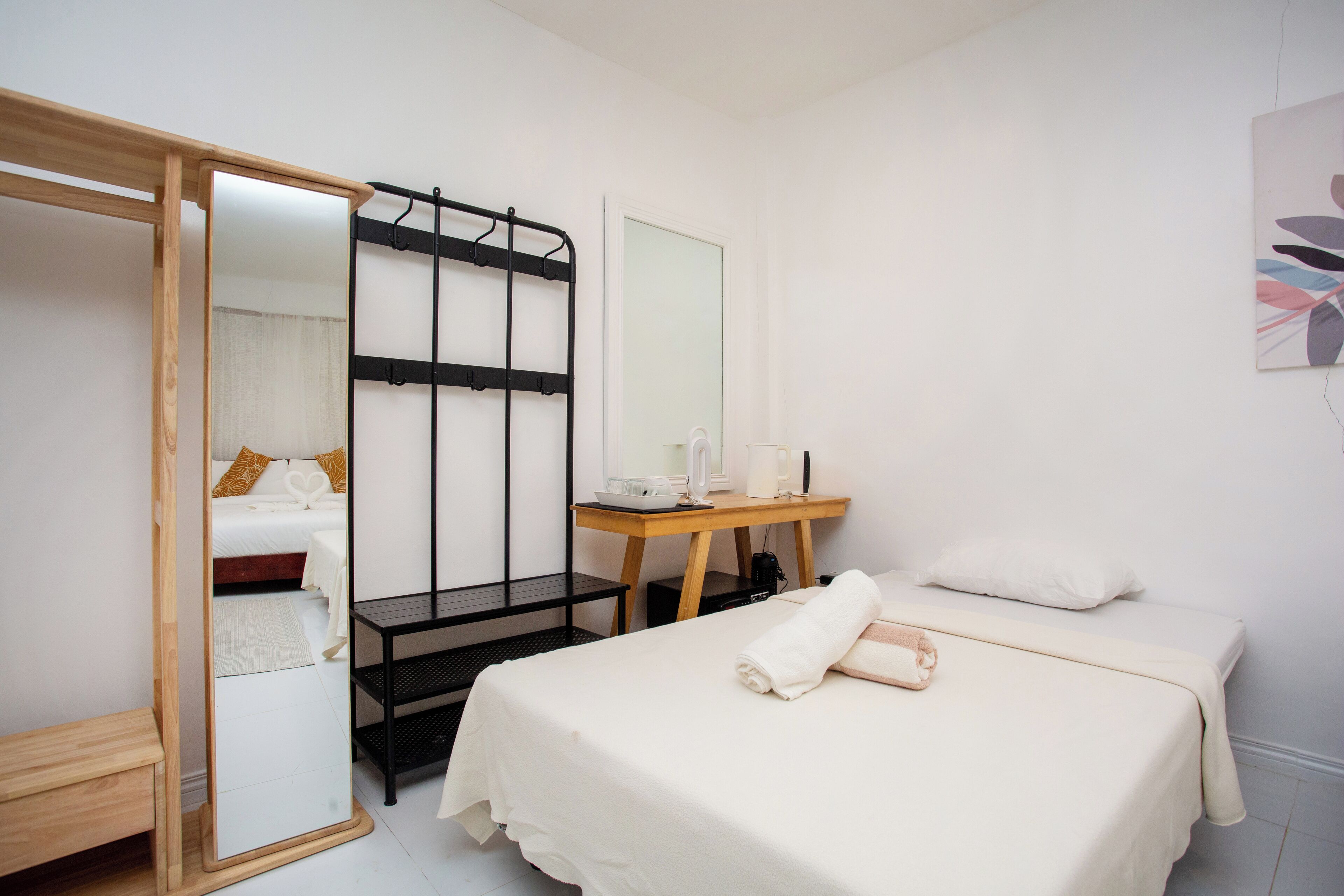 Une chambre d’hôtel comprenant un lit, un banc en bois, un bureau avec un miroir et une armoire.
