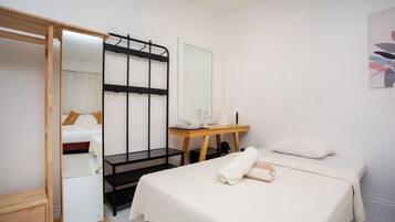 Une chambre d’hôtel comprenant un lit, un banc en bois, un bureau avec un miroir et une armoire.