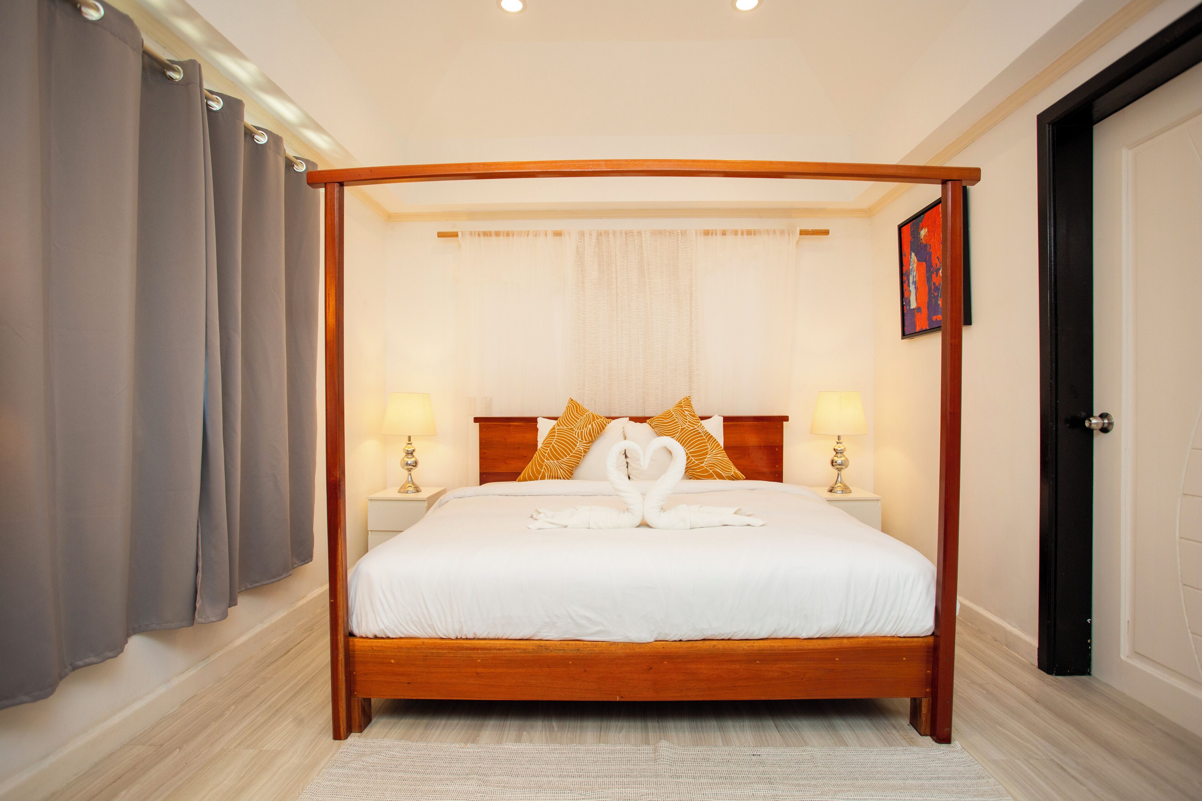 A four-poster bed with a white bedspread and two lamps on either side.