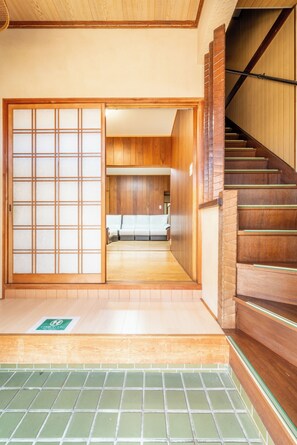 A traditional Japanese-style interior with a wooden staircase, sliding doors, and a sofa in the background.