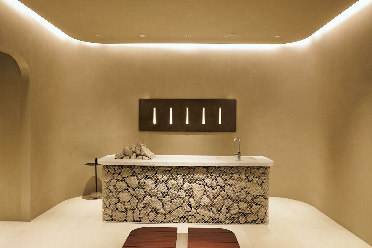 A modern bathroom with a freestanding bathtub, a wall-mounted light fixture, and a textured wall design.