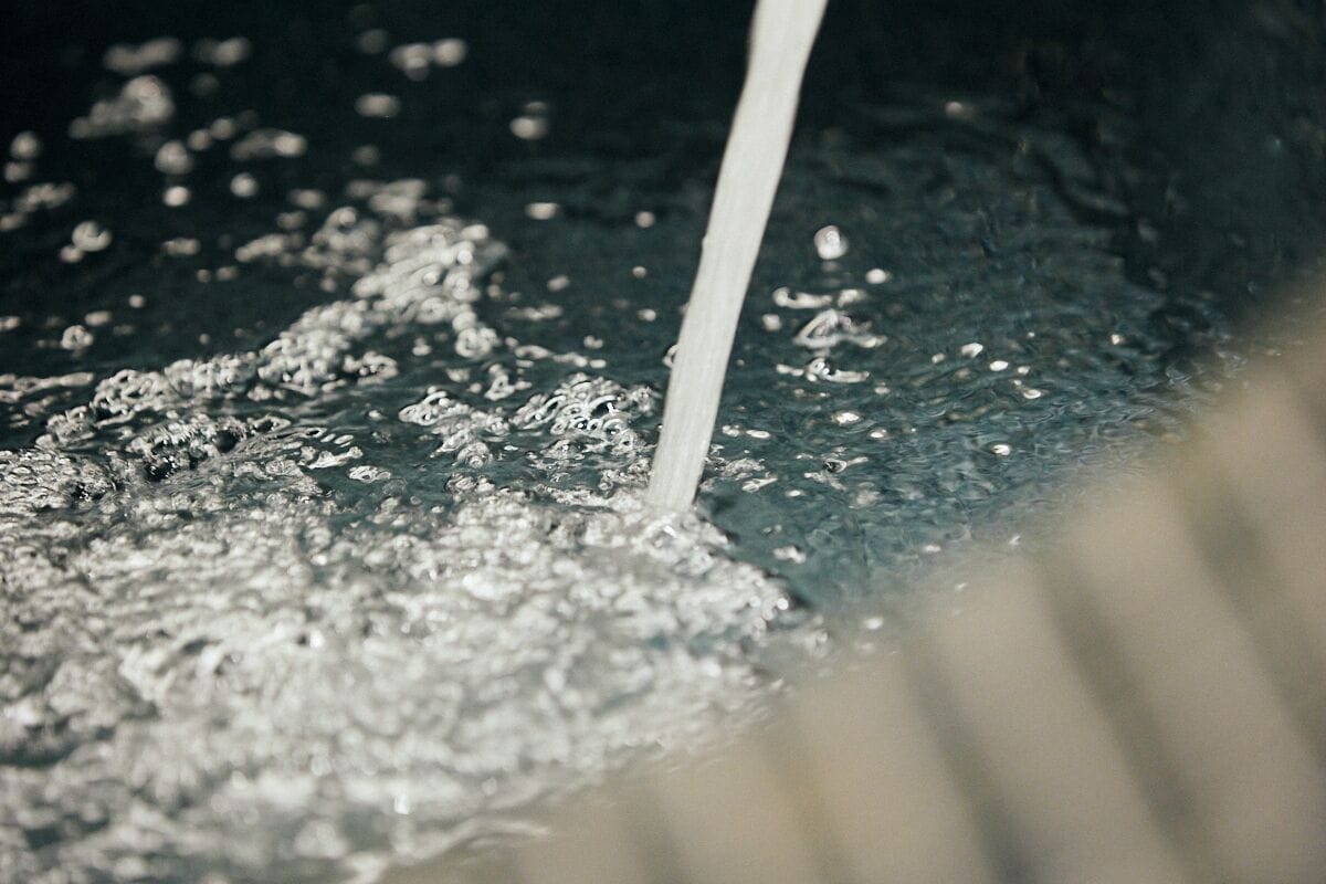 A close-up of water flowing into a pool, creating ripples and bubbles.