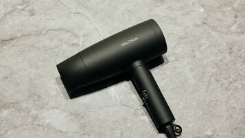 A black hair dryer with a cord on a textured surface.