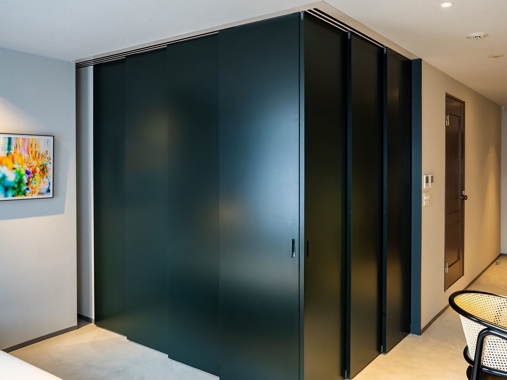 A modern room with a large sliding door, a small table, and a door with a light switch.