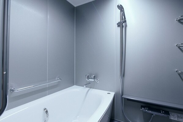 A modern bathroom with a white bathtub, a shower with a handheld showerhead, and a towel rack. - TRAN.SCENDER HOTEL Yokohama (Yokohama)