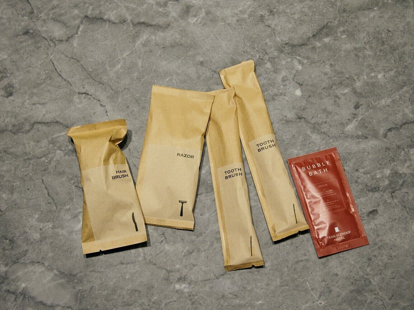 A set of grooming products including razors, hairbrushes, and a bubble bath, laid out on a textured surface.
